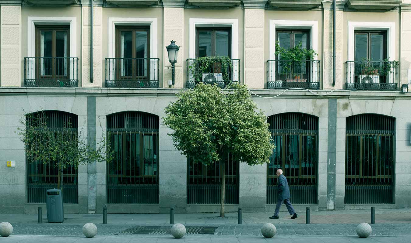 Foto de un señor mayor cruzando la Plaza de Santa Cruz en Madrid 